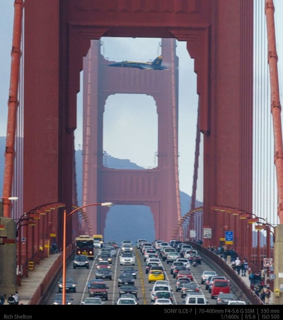F-18 en vuelo de demostración entre las torres del Golden Gate, mientras circulan por él coches y peatones